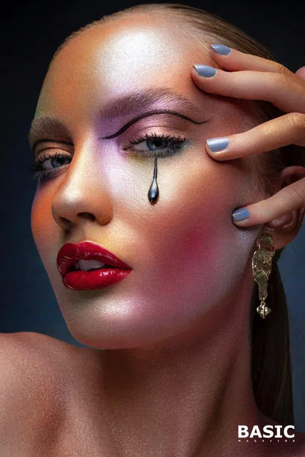 Beauty portrait with luminous pastel eye makeup, a black teardrop, red lips and pale blue nails