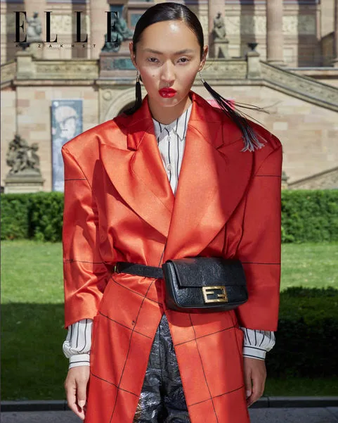 Model in an orange-red oversized coat with red lips, on an ELLE Kazakhstan page
